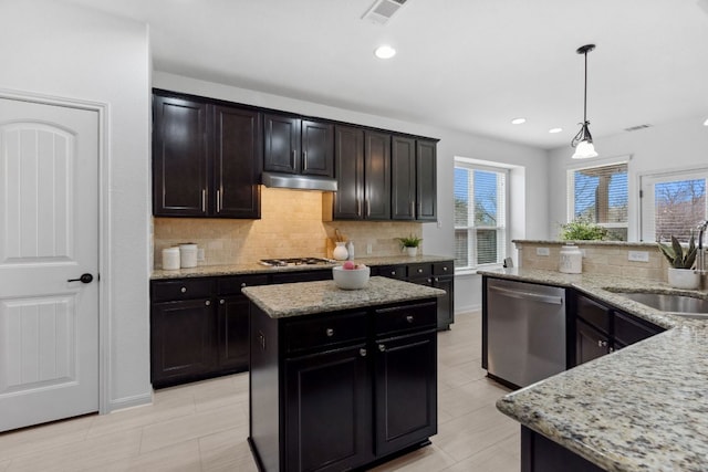 kitchen with visible vents, a kitchen island, appliances with stainless steel finishes, under cabinet range hood, and a sink