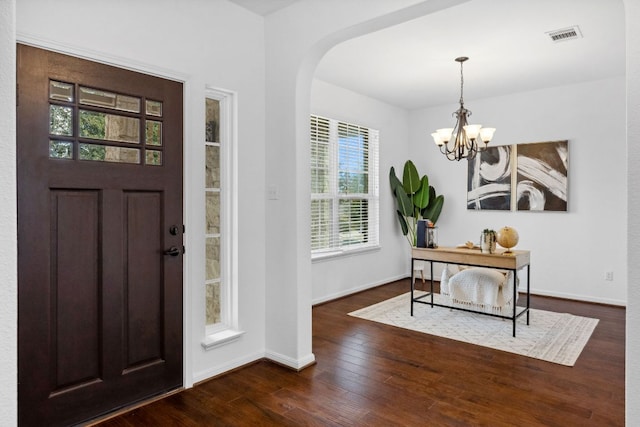 foyer entrance with dark wood-style floors, a chandelier, visible vents, and baseboards