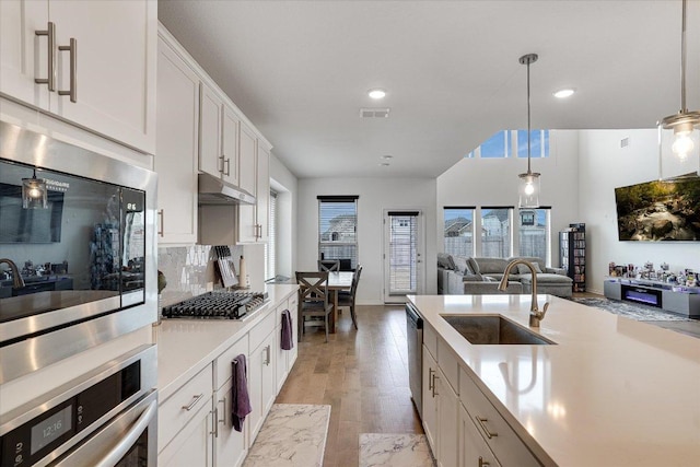 kitchen featuring stainless steel appliances, light countertops, visible vents, a sink, and under cabinet range hood