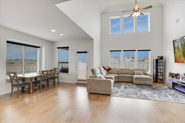 living area featuring light wood finished floors, baseboards, visible vents, and a ceiling fan