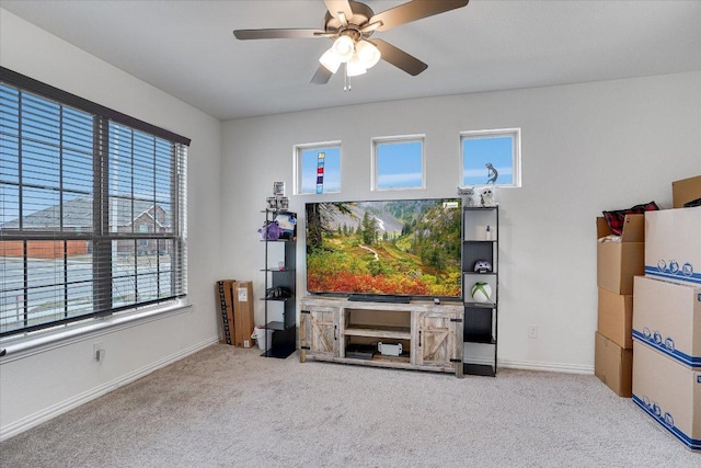 carpeted living area with baseboards and a ceiling fan