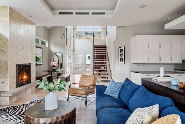 living room featuring a tile fireplace, a high ceiling, and stairs