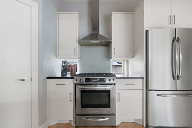 kitchen with white cabinetry, a healthy amount of sunlight, appliances with stainless steel finishes, backsplash, and wall chimney exhaust hood