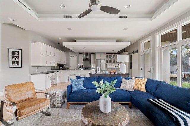 living room with a ceiling fan, a tray ceiling, visible vents, and recessed lighting