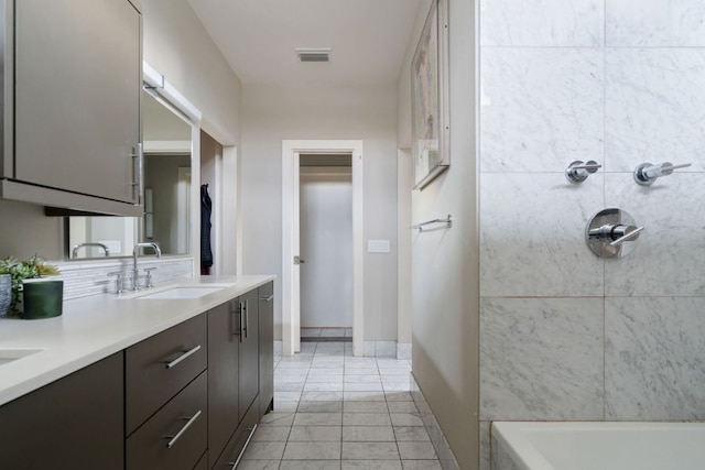 bathroom featuring a sink, visible vents, baseboards, decorative backsplash, and double vanity