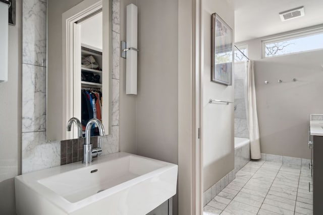 bathroom with marble finish floor, visible vents, a walk in closet, and vanity