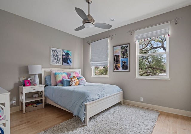 bedroom featuring a ceiling fan, baseboards, and wood finished floors