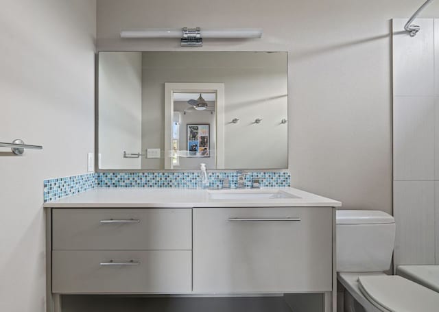 full bath featuring toilet, vanity, and decorative backsplash