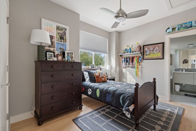 bedroom with light wood finished floors, baseboards, and connected bathroom