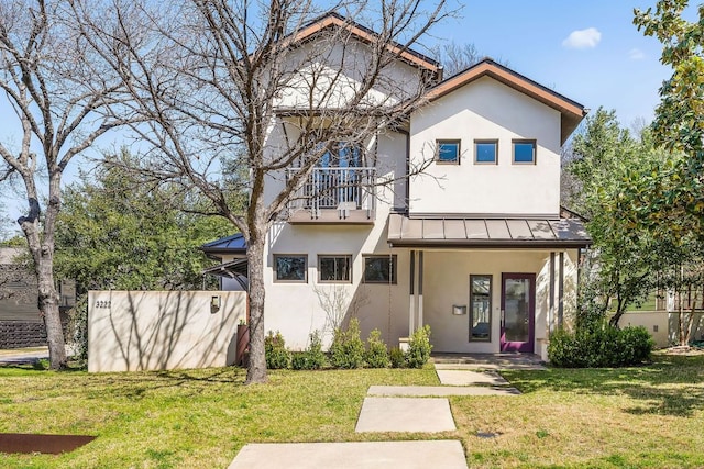 view of front of property with a standing seam roof, stucco siding, and a front yard