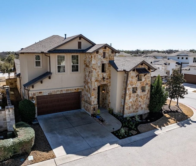 view of front of property with a garage, concrete driveway, stone siding, and stucco siding