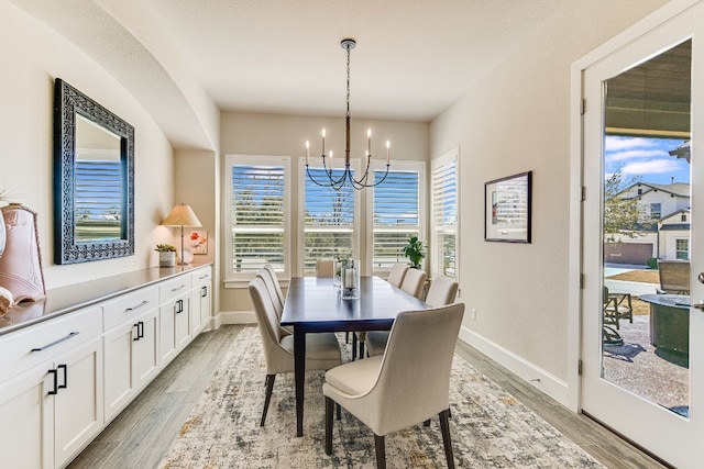 dining space featuring wood tiled floor, baseboards, and an inviting chandelier