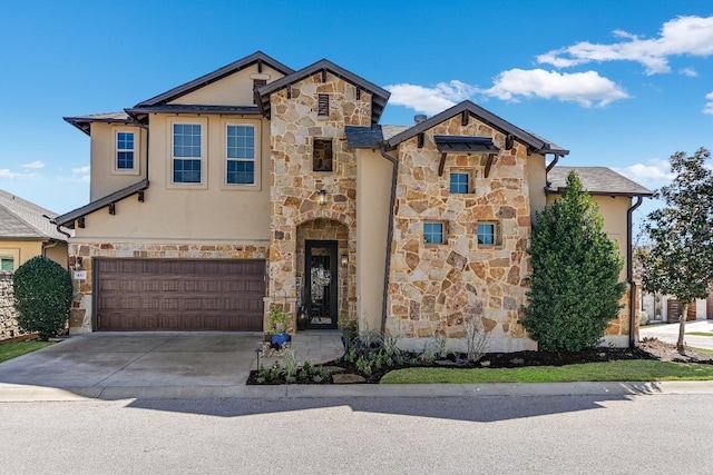 view of front of house featuring stone siding, an attached garage, concrete driveway, and stucco siding