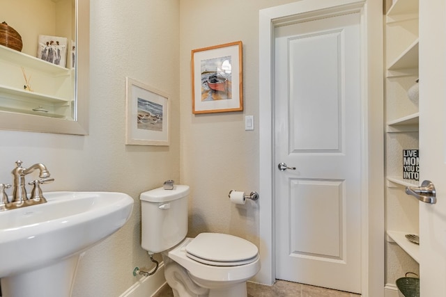 half bath featuring tile patterned flooring, a sink, and toilet