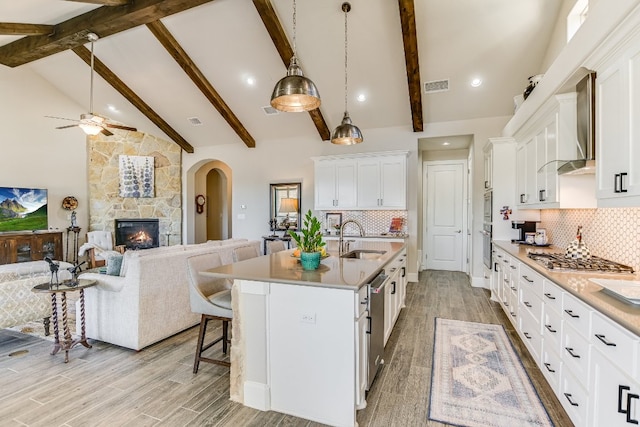 kitchen with open floor plan, wall chimney exhaust hood, light wood finished floors, and a sink