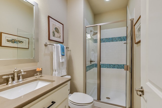 bathroom with a stall shower, a textured wall, vanity, and toilet