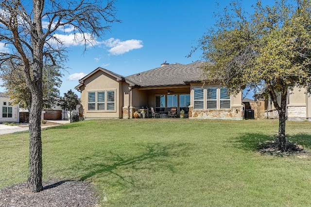 rear view of property with a yard, a shingled roof, stone siding, and stucco siding