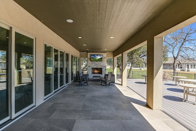 view of patio with fence and an outdoor stone fireplace