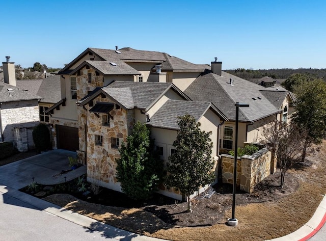 french country home with driveway, a garage, a shingled roof, stone siding, and stucco siding