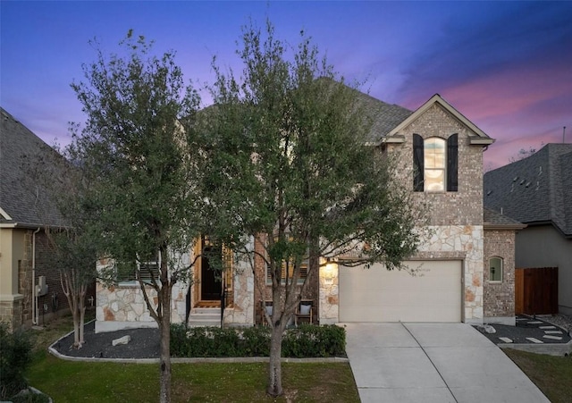 view of front facade featuring driveway, stone siding, an attached garage, and a shingled roof