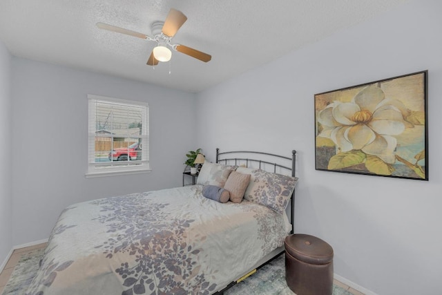 bedroom featuring a ceiling fan, a textured ceiling, and baseboards