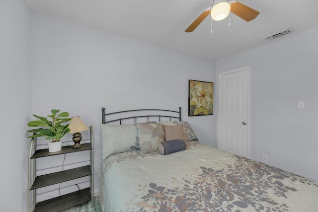 bedroom featuring ceiling fan, visible vents, and a textured ceiling