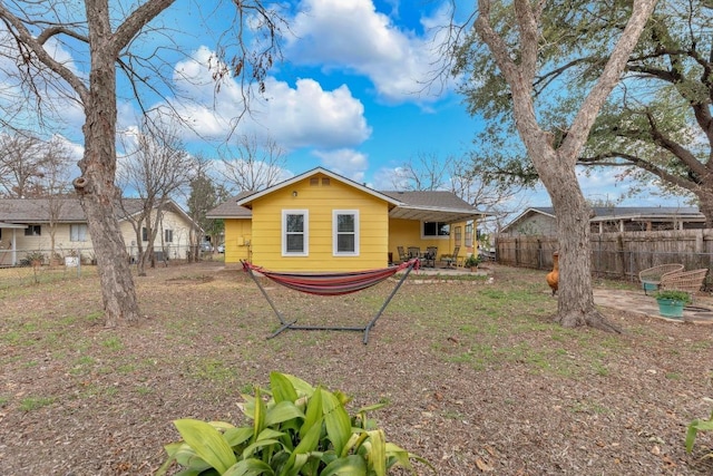 back of property with a fenced backyard and a patio