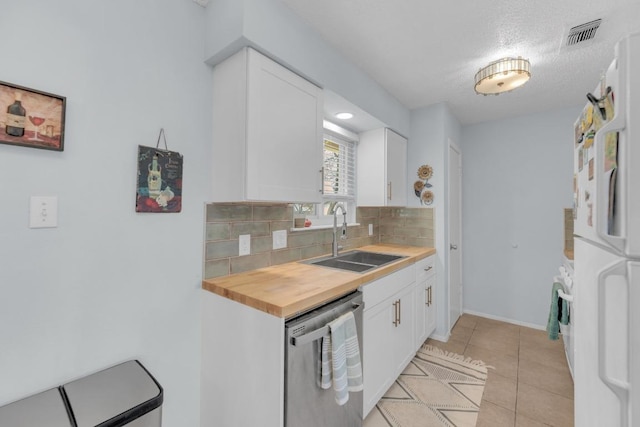 kitchen with light tile patterned floors, a sink, backsplash, freestanding refrigerator, and dishwasher