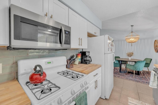 kitchen with white appliances, light tile patterned floors, a textured ceiling, white cabinetry, and pendant lighting