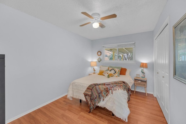 bedroom featuring a closet, a textured ceiling, baseboards, and wood finished floors