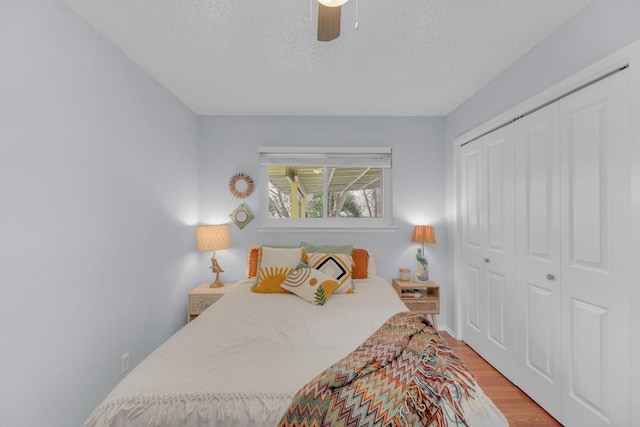 bedroom featuring a textured ceiling, ceiling fan, a closet, and light wood-style flooring