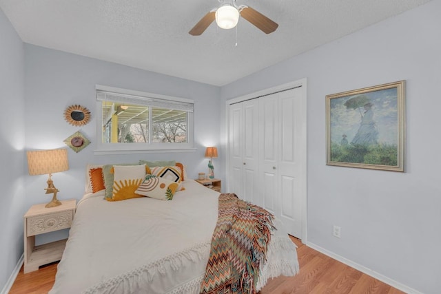 bedroom featuring a ceiling fan, a closet, light wood-style flooring, and baseboards