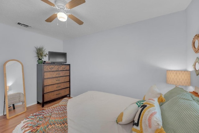 bedroom featuring visible vents, ceiling fan, a textured ceiling, and light wood finished floors