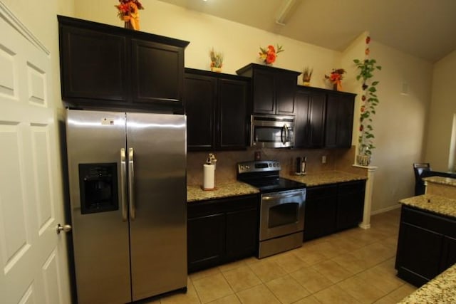 kitchen with light stone countertops, tasteful backsplash, light tile patterned floors, and stainless steel appliances