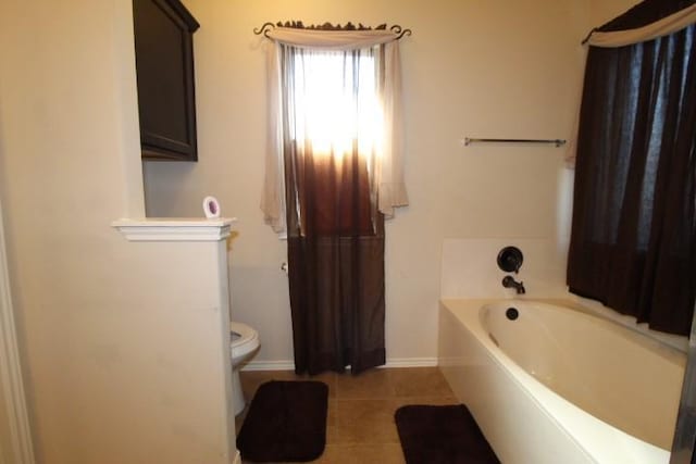 full bathroom featuring tile patterned flooring, baseboards, a garden tub, and toilet