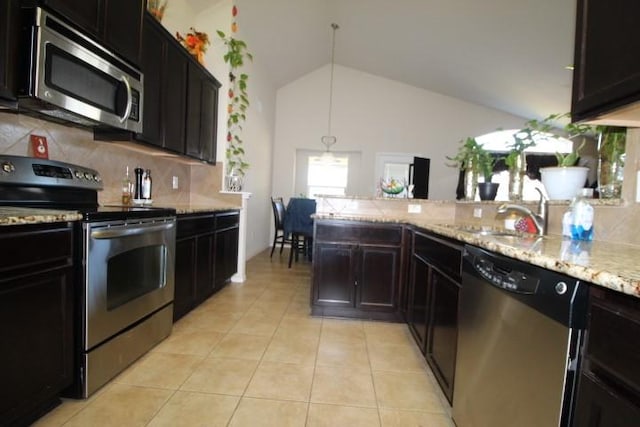 kitchen featuring light tile patterned floors, backsplash, appliances with stainless steel finishes, vaulted ceiling, and a sink