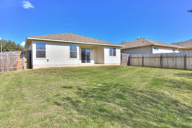 rear view of property featuring a fenced backyard, a lawn, and stucco siding