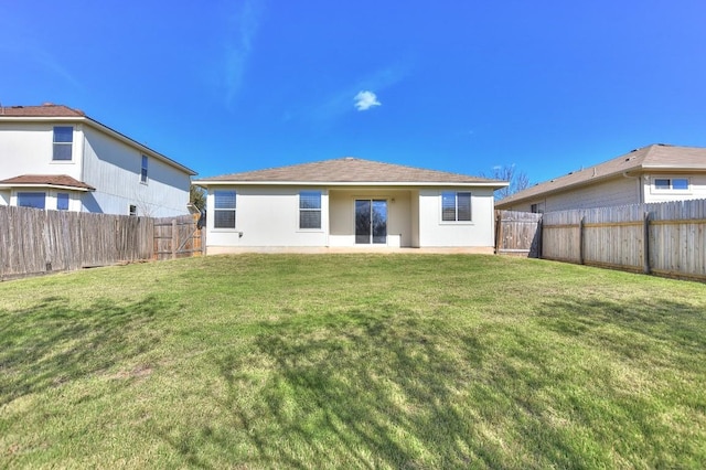 rear view of property with a fenced backyard, a lawn, and stucco siding