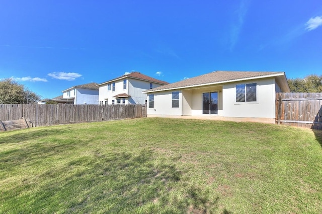 rear view of property featuring a fenced backyard, a yard, and stucco siding