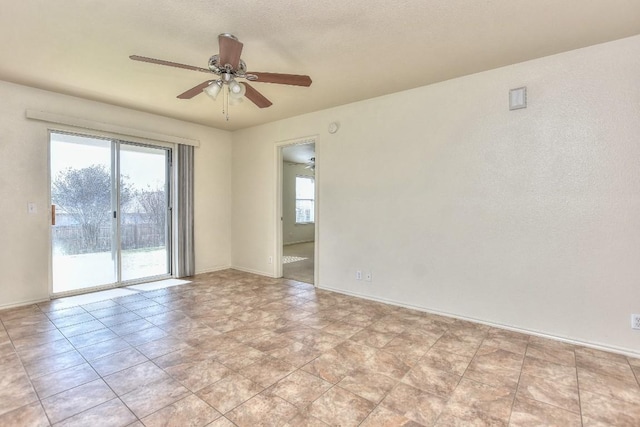 empty room with ceiling fan and baseboards