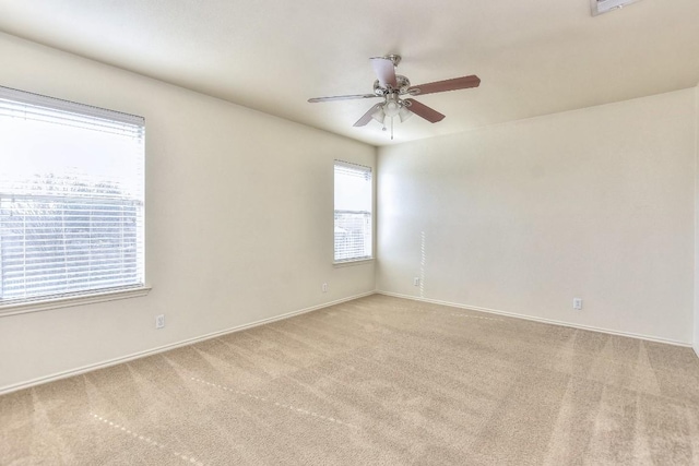 carpeted spare room with ceiling fan and baseboards