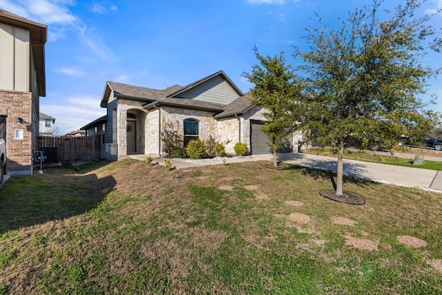 view of front of home featuring concrete driveway, fence, a garage, stone siding, and a front lawn