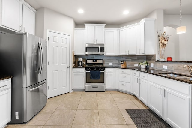 kitchen with light tile patterned floors, stainless steel appliances, decorative backsplash, white cabinetry, and a sink