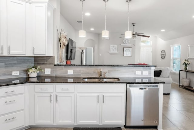 kitchen with light tile patterned floors, a sink, decorative backsplash, dishwasher, and dark stone countertops