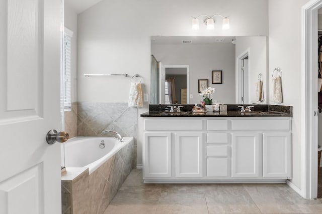 bathroom featuring double vanity, visible vents, a sink, and a bath