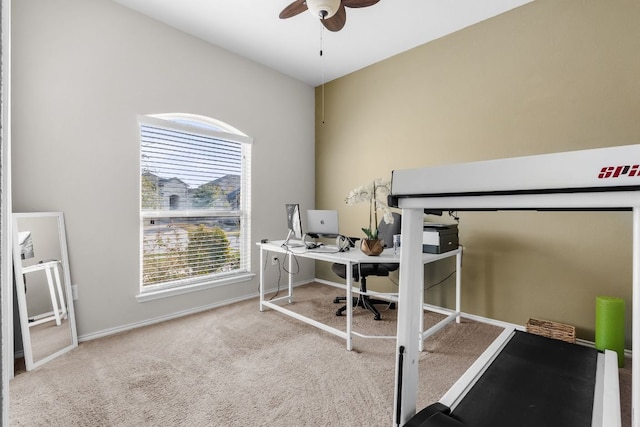 carpeted office space featuring ceiling fan and baseboards