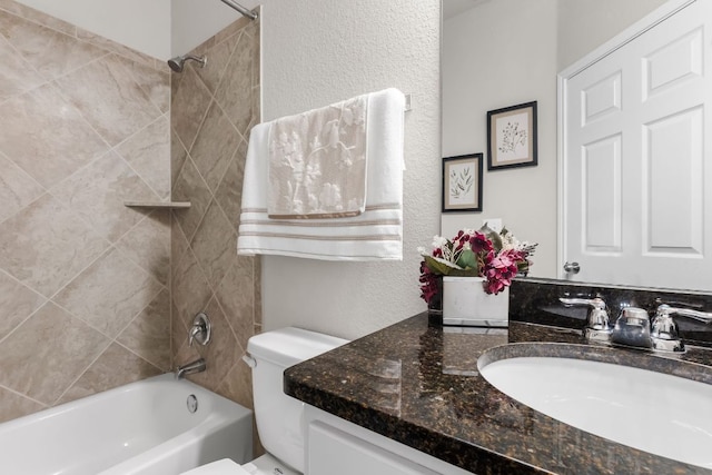 full bath featuring toilet, a textured wall, washtub / shower combination, and vanity