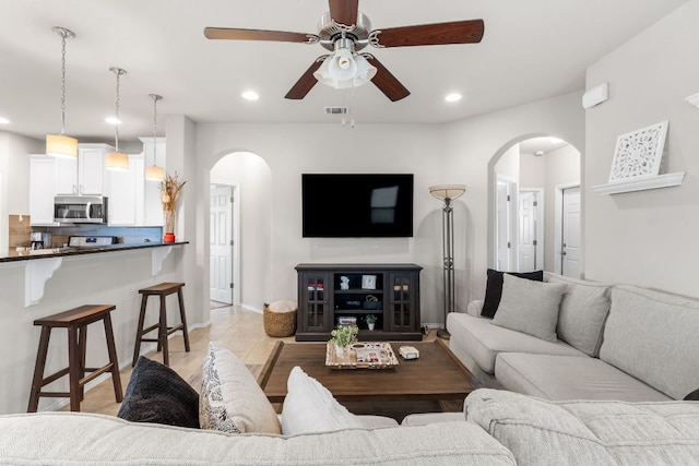 living area with arched walkways, light tile patterned floors, visible vents, and recessed lighting