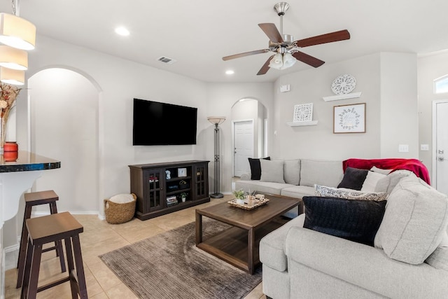 living area featuring light tile patterned floors, visible vents, arched walkways, a ceiling fan, and recessed lighting