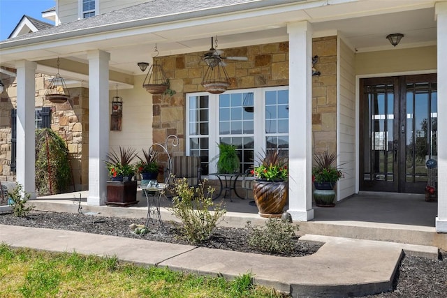 doorway to property with covered porch, roof with shingles, stone siding, and french doors